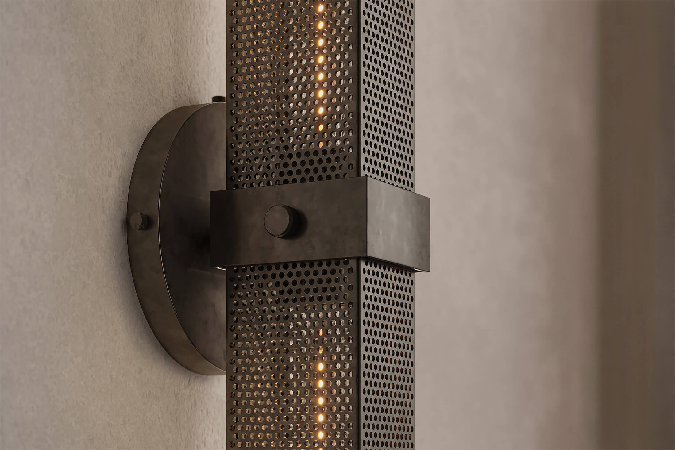 Close-up view of the architectural designer Baffle Sconce (Tandem), an industrial-inspired wall light featuring hand-finished perforated steel for genuine, utilitarian elegance.