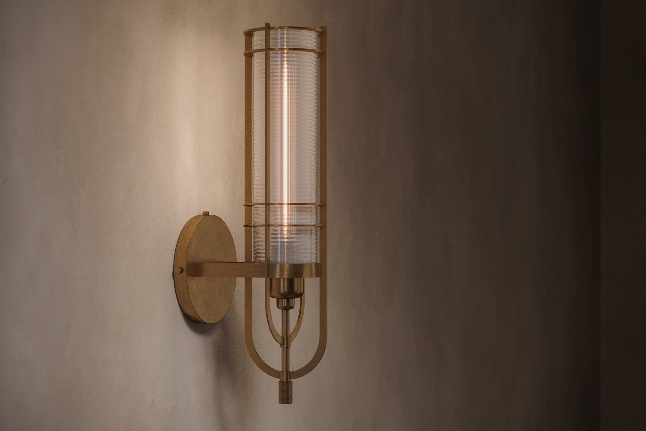 Modern architectural lighting featuring the Batten Sconce, a wall sconce in hand-finished solid brass and ribbed glass.
