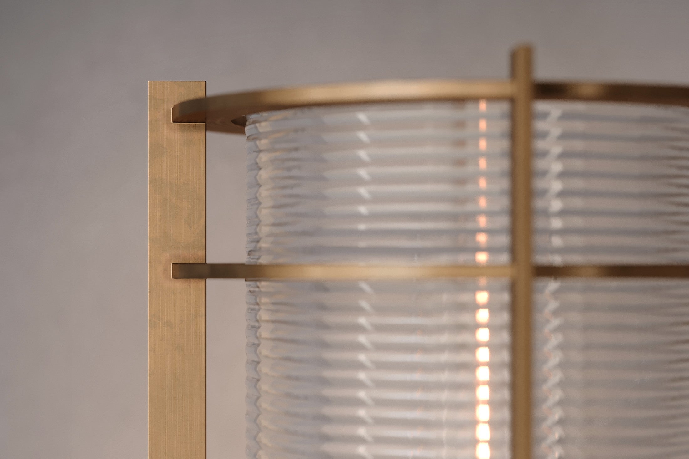 Close-up of the Batten Sconce, a modern wall sconce featuring hand-finished solid brass and ribbed glass.
