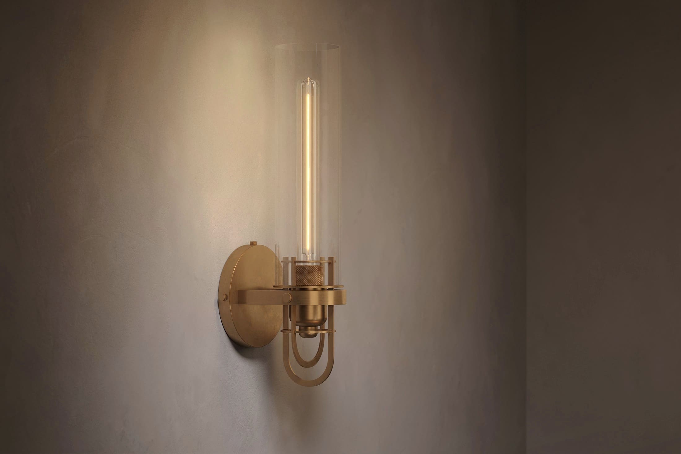 Modern architectural lighting featuring the Beacon Sconce, a wall light in hand-finished solid brass and a heavy glass cylinder.