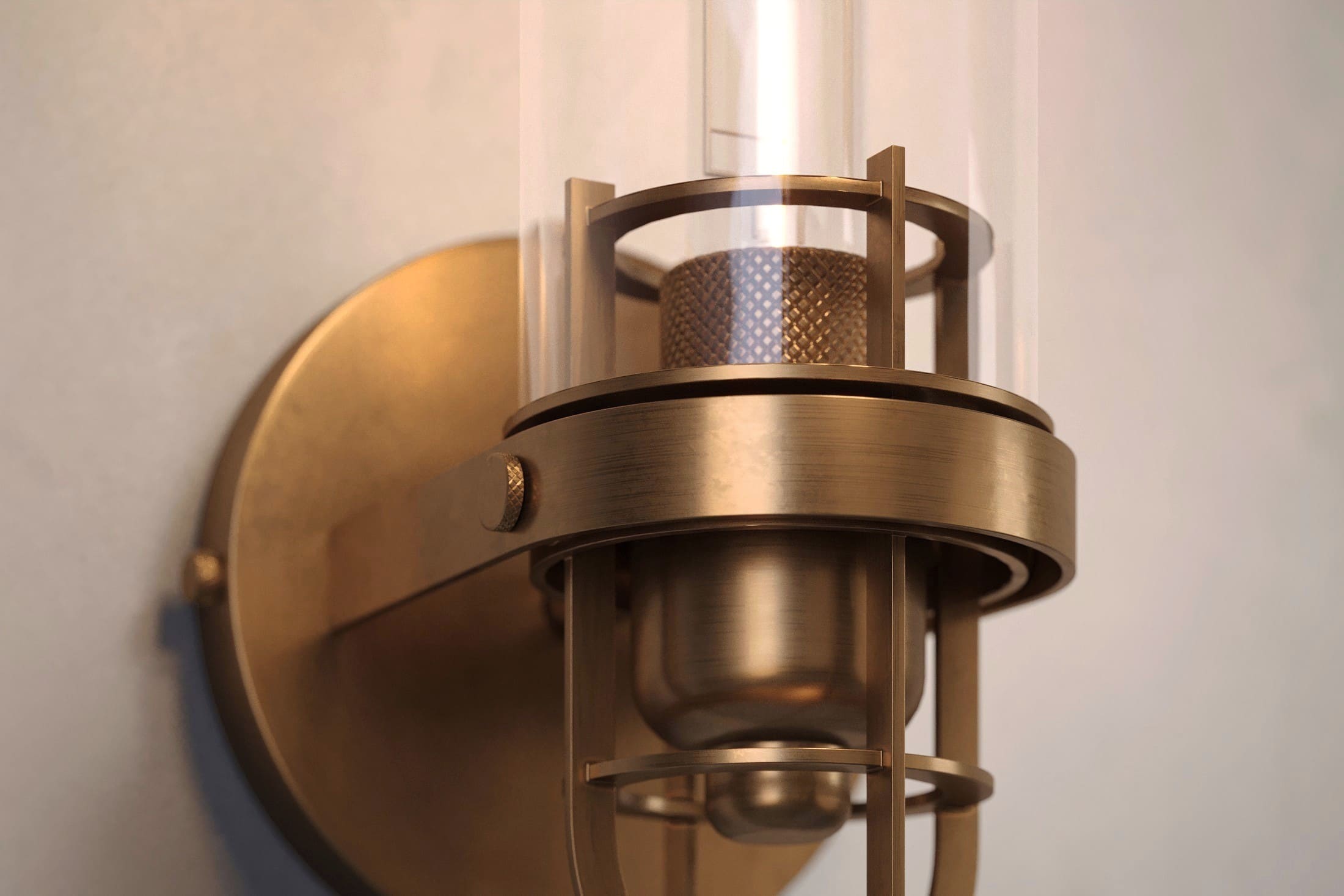 Close-up of the Beacon Sconce, a modern wall light featuring hand-finished solid brass and a heavy glass cylinder.