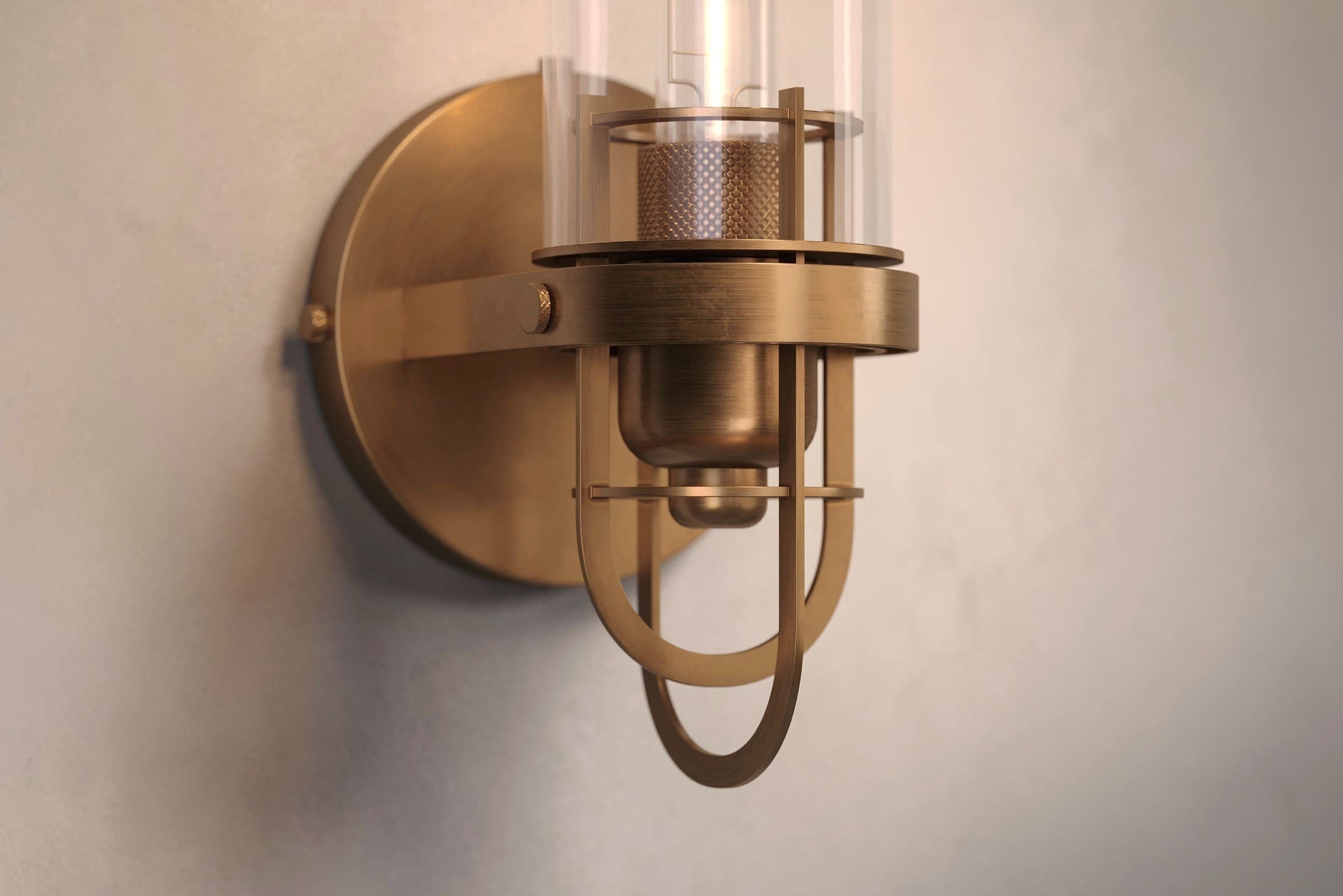 Close-up of the Beacon Sconce, a modern wall light featuring hand-finished solid brass and a heavy glass cylinder.