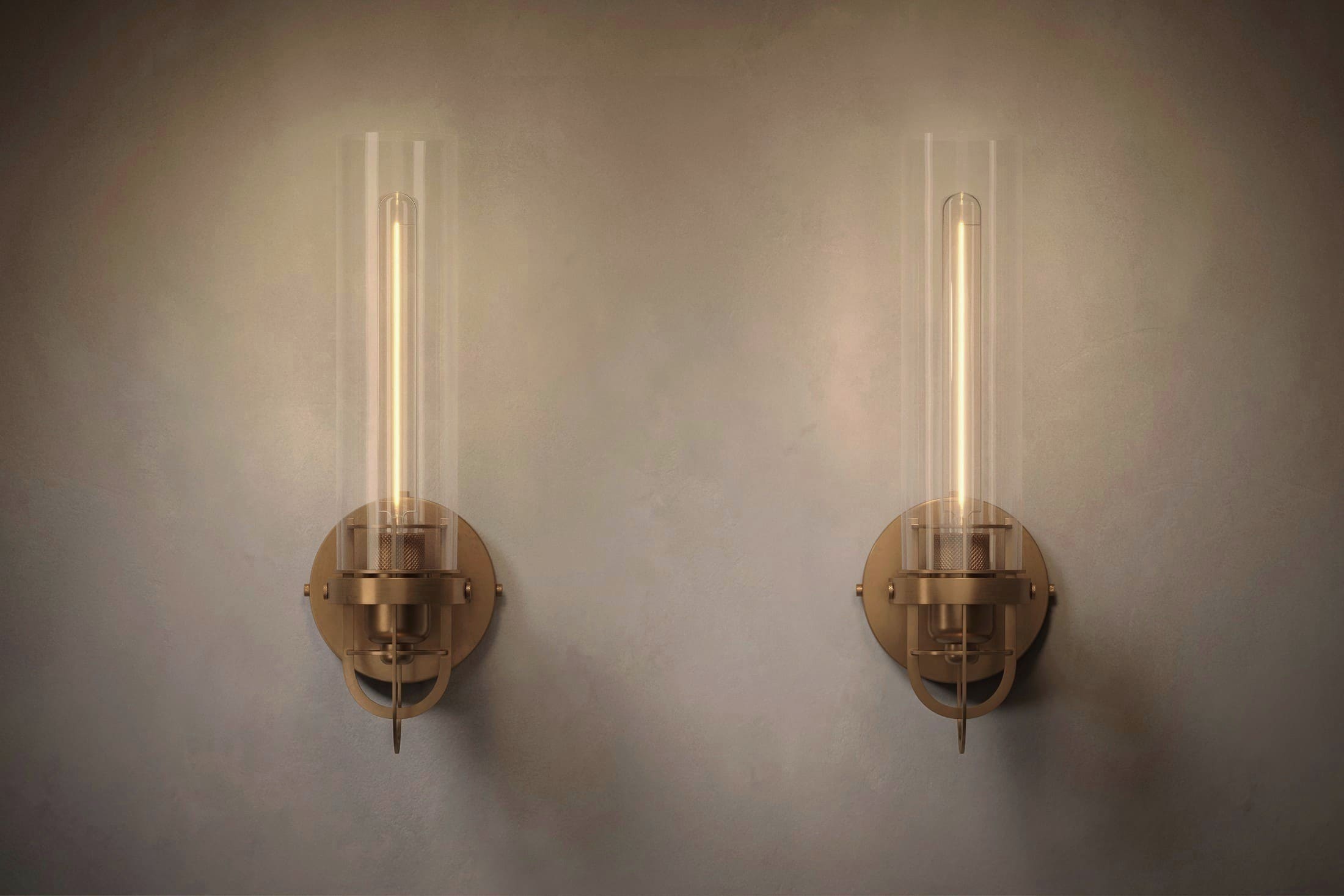 Architectural lighting featuring two Beacon Sconce fixtures in hand-finished solid brass and a heavy glass cylinder.