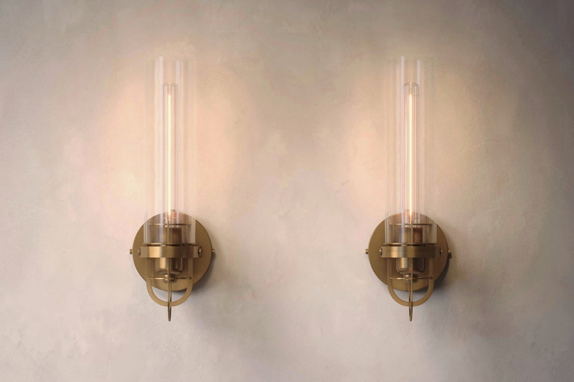 Architectural lighting featuring two Beacon Sconce fixtures in hand-finished solid brass and a heavy glass cylinder.