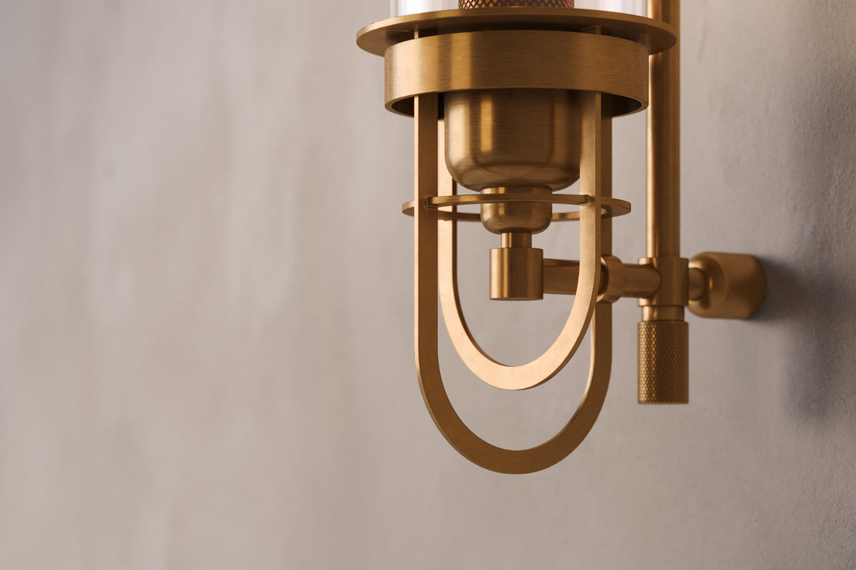 Close-up view of the designer Belay Sconce, a nautically-inspired decorative wall light featuring hand-finished solid brass and heavy glass for authentic, artisanal elegance.