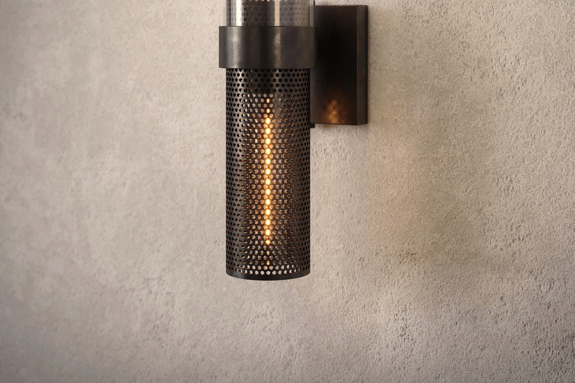 Close-up of the Carbide Sconce, a modern wall sconce featuring hand-finished perforated metal and glass.