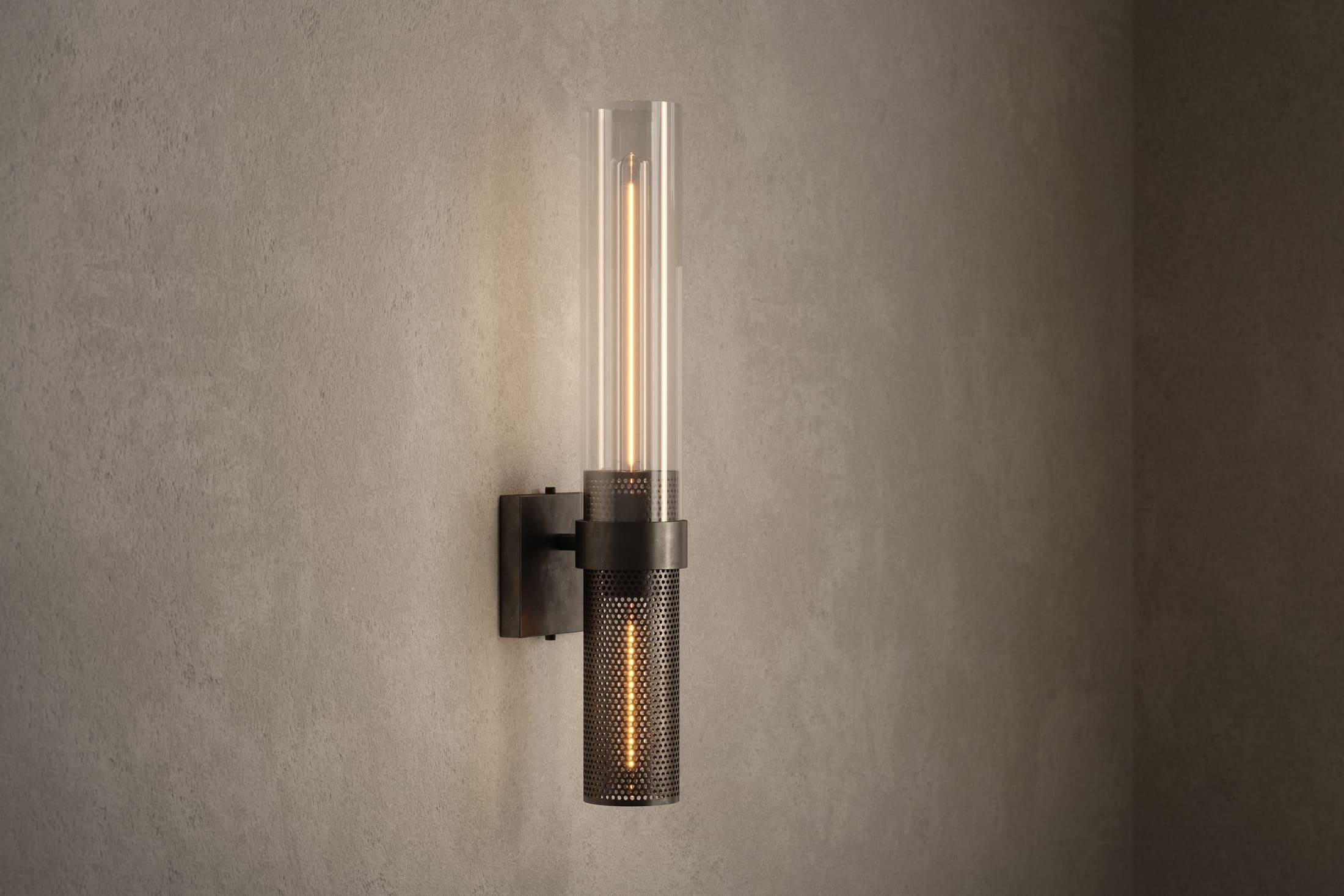 Architectural lighting featuring the Carbide Sconce, a modern wall sconce in hand-finished perforated metal and glass.