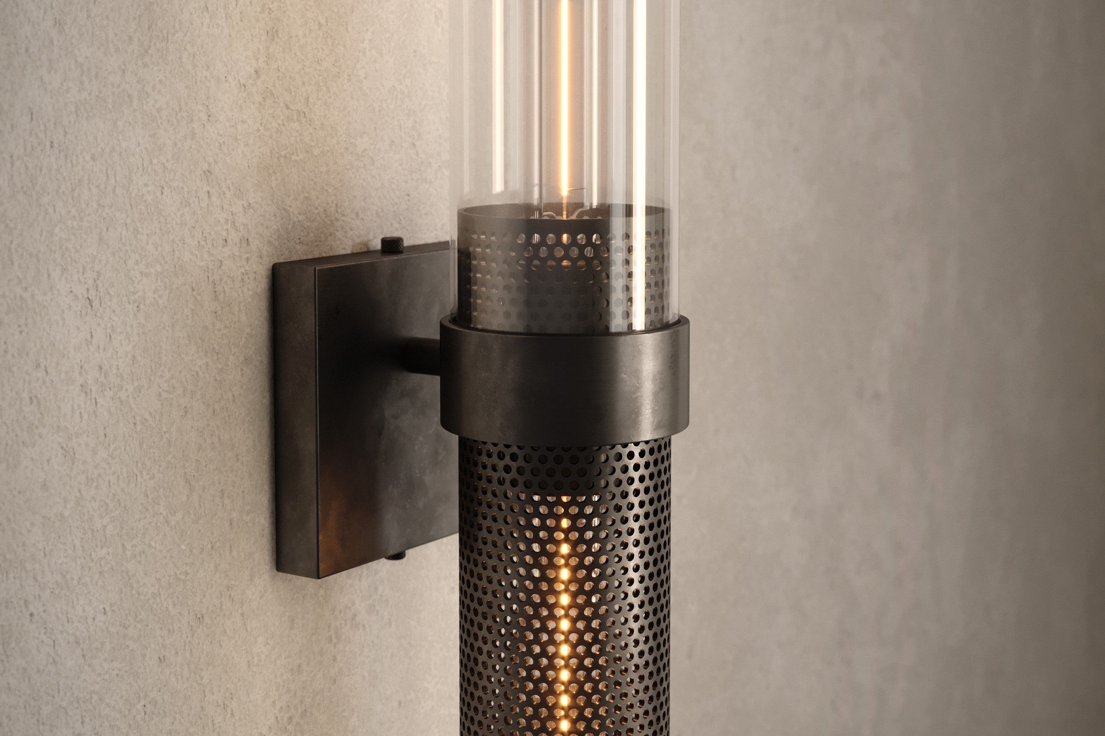 Close-up of the Carbide Sconce, a modern wall sconce featuring hand-finished perforated metal and glass.