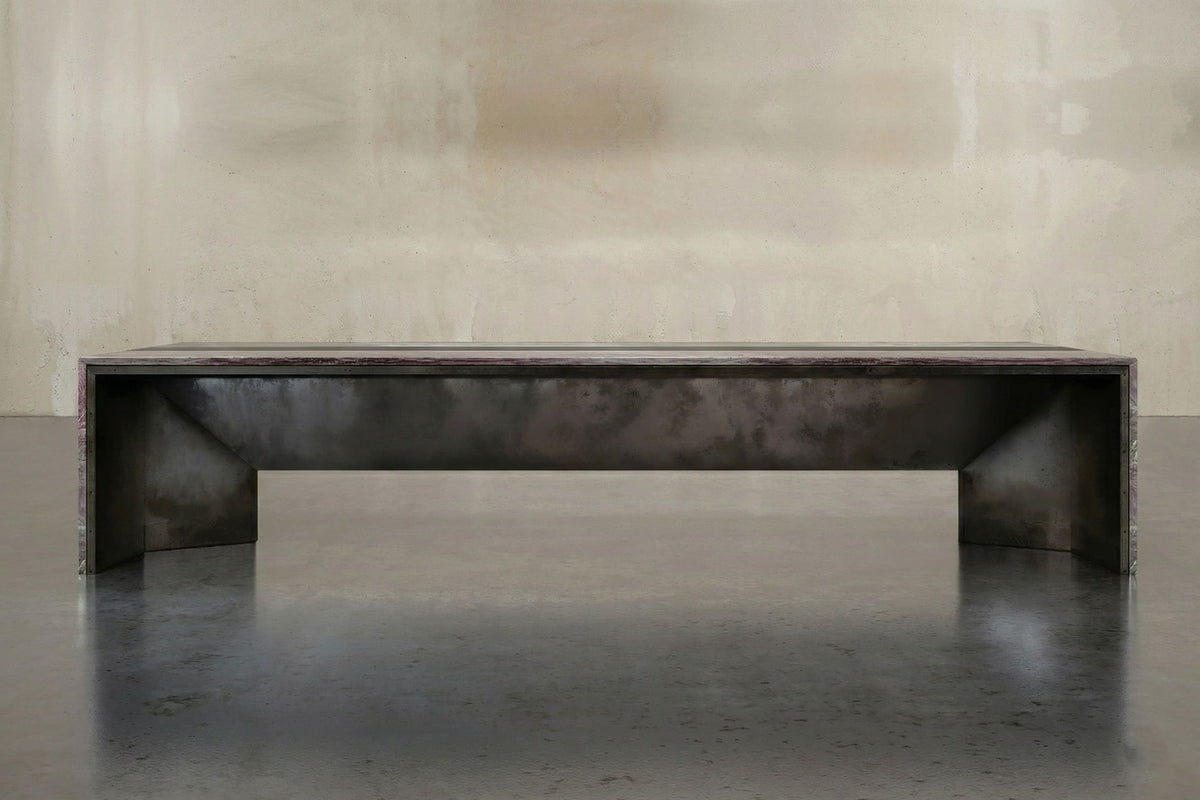 Low monolithic table in stone and dark metal.