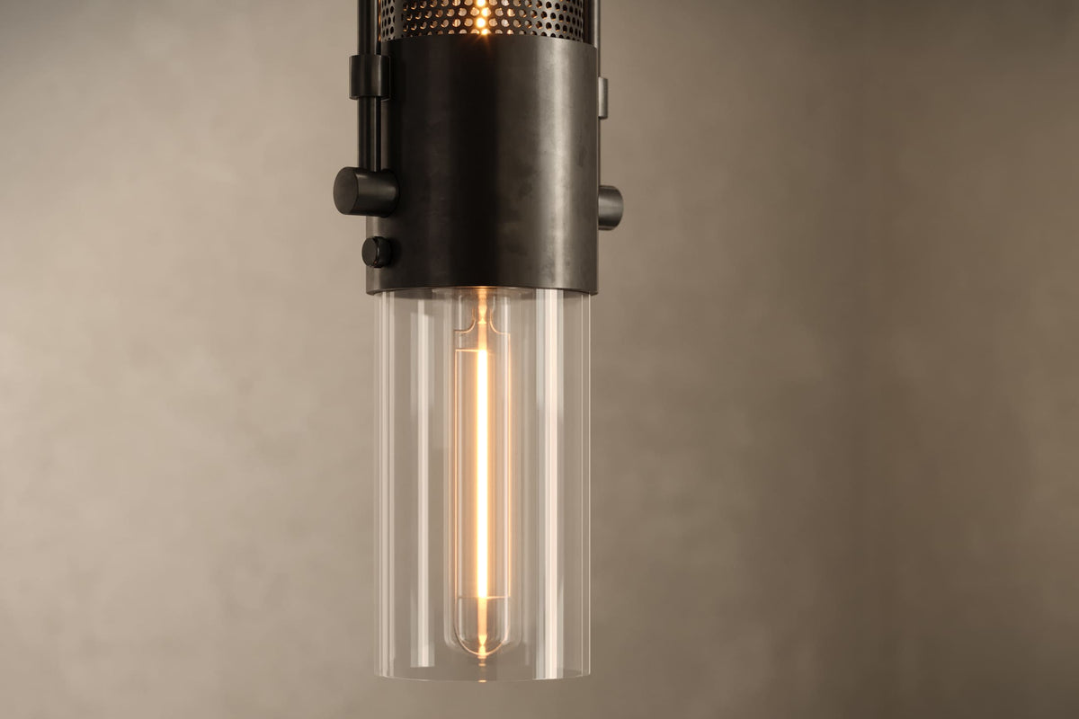 Close-up view of the architectural designer Plumb Pendant, an industrial-inspired pendant light featuring hand-finished perforated steel and heavy glass for genuine, utilitarian elegance.